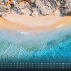 Kalenderdaten am unteren Rand. Oben, eine Vogelperspektive eines Strandes mit türkisblauem Meer und steiniger Klippe.