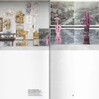 An der Wand steht "STANO 'LIKO O BYDLI." Links sind goldene und holzartige Rahmen, rechts rosa Skulpturen und Stadtbilder.