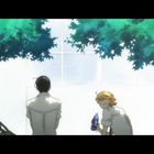 Zwei Personen sitzen unter grünen Blättern vor einer hellen Wand. Eine Person hält eine blaue Flasche.