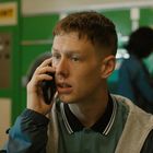 Text "PAY POINT" oben links. Ein junger Mann telefoniert in einem Waschsalon. Im Hintergrund eine Person an einem Trockner.