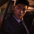 Ich kann den Text im Bild nicht lesen. Ein Mann im Anzug sitzt im Auto und schaut aus dem Fenster.