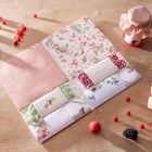 Gemustertes Papier, Schnüre und Beeren auf Holz. Marmeladenglas mit rot-weiß kariertem Stoff oben links.