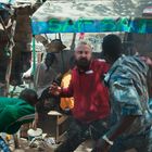 Der Text "SAT SAT" steht über einem improvisierten Straßenstand. Drei Männer wirken in Bewegung, als ob sie streiten.