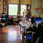 Person in einem unordentlichen Zimmer mit vielen Büchern, einem Fernseher und Baseball-Fahnen an der Wand.