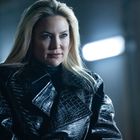 Keine erkennbaren Texte. Eine Frau mit langem blondem Haar trägt einen schwarzen Leder-Mantel im schwachen Licht.