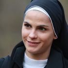 Eine Frau in einem Nonnenschleier, lächelt leicht, im Freien. Sie trägt ein schwarzes Habit und einen weißen Kragen.