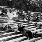 Keine sichtbaren Texte. Menschen liegen auf Treppen, ein Kinderwagen rollt die Stufen hinunter.