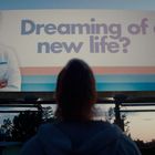 Werbungstext: "Dreaming of a new life?" Logo: "SOMNIUM". Person in Arztkleidung lächelt, Bäume im Hintergrund.