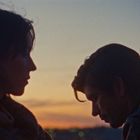 Zwei Personen seitlich im Profil bei Sonnenuntergang. Der Himmel ist in warmen Farbtönen gefärbt.