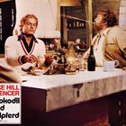 "Terence Hill Bud Spencer Das Krokodil und sein Nilpferd." Zwei Männer sitzen an einem Tisch, essen, darunter eine Flasche und eine Lampe.