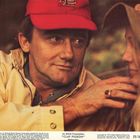 An MGM Presentation: "CLAY PIGEON". Ein Mann mit roter Kappe schaut eine Frau an. Beiden tragen Jacken, Atmosphäre wirkt entspannt.