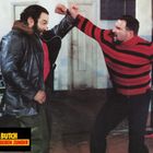 "Toby & Butch, vier Fäuste geben Zunder." Zwei Männer sind im Streit; einer trägt eine Lederjacke, der andere einen gestreiften Pullover.
