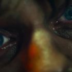 Nahaufnahme von zwei blauen Augen, die intensiv schauen, umrahmt von rostroten Schatten.