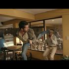 Zwei Männer kämpfen in einem kleinen Café. Einer führt einen Kick aus, während der andere versucht auszuweichen.