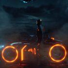 Keine sichtbaren Texte. Eine Figur in einem futuristischen Anzug steht neben einem neonbeleuchteten Motorrad in dunkler Umgebung.