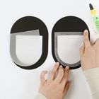 Zwei schwarze ovale Formen, teils mit transparentem Papier bedeckt, werden von Händen bearbeitet; eine Klebeflasche liegt daneben.
