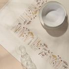 Gestickte Blumenmuster säumen weißen Stoff, darauf eine weiße Schale und zwei klare Gläser.