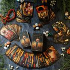 „Bernsteinmond Tarot“ und „Regina Barlachowski“ auf Karten. Farbenfrohe Tarotkarten mit Menschenbildern, Edelsteine und Pflanzen.