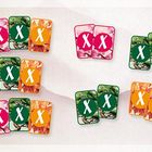 Kartenstapel in vier Farben: Pink, Grün, Orange. Vorderseiten zeigen "X". Hintergrund Blattmuster.