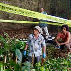 „Police Nationale - Zone Interdite“ steht auf gelbem Band. Drei Männer sind in einem Waldgebiet, umgeben von Pflanzen.