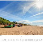 Sonne und Strand in Międzyzdroje, viele bunte Boote am sandigen Ufer, blauer Himmel mit Wolken und Sonnenstrahlen.