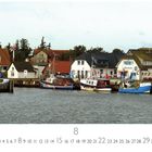 Logo: "Hiddensee, Hafen". Mehrere Boote vor einer Reihe von Gebäuden am Wasser. Bäume im Hintergrund.