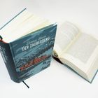 Zwei Bücher: "Thomas Mann: Der Zauberberg". Eines geschlossen mit Bergmotiv, das andere aufgeschlagen.