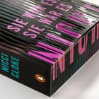 Texte: "SIE WAR ES NICHT", "NICCI CLOKE". Design mit schwarz-lilanen Streifen und einem kleinen Pinguin-Logo.