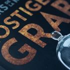 ROSTIGES GRAB, ein Bereich zeigt einen roten Aufkleber. Dazu eine Glasglocke über einem kleinen Käfer.