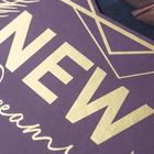 "NEW Dreams" in goldener Schrift auf violettem Hintergrund, verziert mit geometrischen Formen und Blattmustern.