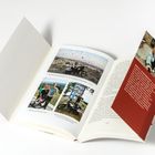 Eine offene Seite eines Buches zeigt drei Fotos mit Bildunterschriften. Daneben ein rotes Lesezeichen mit einem Porträt.