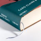 "Caro Claire Burke", "Heyne" auf einem Buchrücken. Das Buch hat einen blauen Umschlag und ein Lesezeichen.