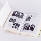 Ein aufgeschlagenes Buch mit schwarzen und weißen Fotos von Menschen. Texte beschreiben historische Ereignisse.