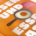 „ESSEN UND ESSEN“ in großen weißen Buchstaben auf orangefarbenem Hintergrund, mit einem Spiegelei in einer Pfanne.