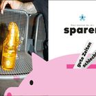 Text: "Das kannst du dir sparen", "gute Zeiten", "schlechte Zeiten". Links eine vergoldete Flasche auf einem Metallsitz, rechts ein rosa Sparschwein.