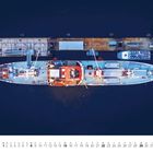 August. Kalender mit Schiff von oben an einem Pier. Großer blauer Rumpf, weiße Aufbauten, Kranarme und Anlegestelle.