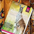 „Australien Westen und Zentrum“, ein Känguru mit Jungtier, darunter rote und weiß gemusterte Didgeridoos.