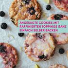 Text: "ANGESAGTE COOKIES MIT RAFFINIERTEN TOPPINGS GANZ EINFACH SELBER BACKEN." 

Bunte Cookies mit Beeren und Glasur auf Backpapier.