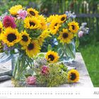 Text "AUGUST" unten. Zwei Vasen mit Sonnenblumen auf Holztisch im Garten. Helle Farben, grüne Wiese im Hintergrund.