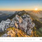 Text: „AUGUST“. Kalender mit Blick auf majestätische Berge bei Sonnenaufgang. Vordergrund: Felsen und Gras.
