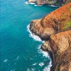 Kalenderseite mit dem Monat "August". Küstenlandschaft mit hohen Klippen und blauem Meer, bewölkter Himmel.