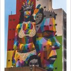 08. Bunte Wandmalerei mit geometrischem Muster: Frau im Bikini, Vogel, Gesicht. Gebäude in kräftigen Farben.