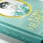 Text: "AUDREY HEPBURN" und "Megan Hess". Ein Buchcover in Türkis mit goldener Schrift und einer Illustration von Audrey Hepburn.