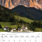 August 2027 Kalender, eine Dorfkirche und Häuser vor beeindruckenden Bergen bei Sonnenuntergang.