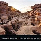 August. Darunter Zahlen 1-31 für die Tage des Monats. Eine felsige Landschaft unter einem Sonnenuntergang mit Schächten und Felsformationen.