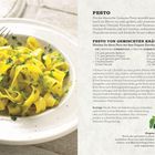 Rezept für Pesto mit gelben Tagliatelle-Nudeln, garniert mit grünen Kräutern auf weißem Teller.