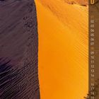 Kalenderseite mit dem Monat August, nummerierte Tage, Luftaufnahme einer orangen Sanddüne in einer Wüstenlandschaft.