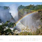 "08 Begegnungen an den Viktoriafällen August 2022. Ein Regenbogen spannt sich über tosende Wasserfälle zwischen Felsen."