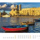 Hafen von Molfetta mit Blick auf den Duomo Vecchio di San Corrado, Apulien. Im Vordergrund liegen bunte Boote im Wasser.
