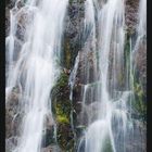 Text: "8", Monatskalender August. Bild eines Wasserfalls, Moose und Felsen sichtbar.